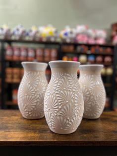 three white vases sitting on top of a wooden table