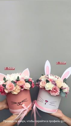 two people are holding up easter baskets with bunny ears on them and flowers in the middle