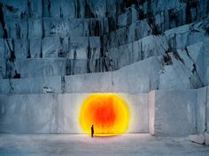 a man standing in front of a large orange light at the end of a tunnel