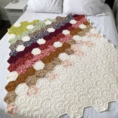 a crocheted blanket is on top of a bed with white sheets and pillows