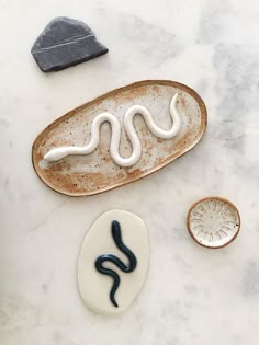 a white and black snake on a plate next to some other items that are sitting on a table