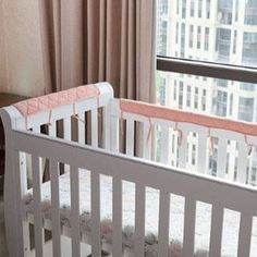 a baby crib in front of a window with cityscape on the wall