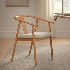 a wooden chair sitting on top of a carpeted floor next to a table and window