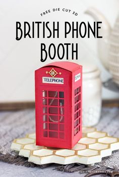 a red phone booth sitting on top of a table next to a white teapot