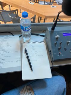 a bottle of water sitting on top of a table next to a notebook