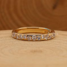 a gold wedding band with five diamonds on it sitting on top of a wooden table