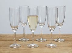 six wine glasses are lined up next to each other on a wooden table with silver rims