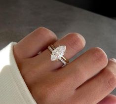 a woman's hand with a diamond ring on top of her finger and an engagement band