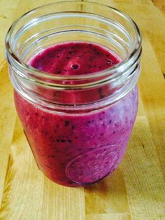 a jar filled with purple liquid sitting on top of a wooden table