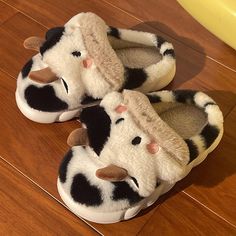 two slippers with black and white spots on them sitting on a wooden floor next to a banana