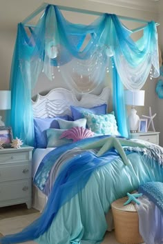 a bedroom decorated in blue and white with an ocean themed canopy bed, chandelier and pillows