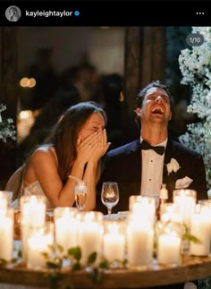 a man and woman sitting next to each other at a table with candles in front of them