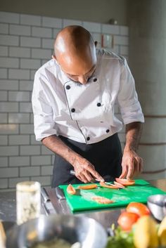 a man in a chef's uniform cutting up vegetables