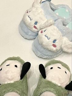 three stuffed animals laying next to each other on top of a white table with blue and green slippers