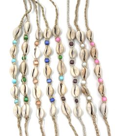 three necklaces with shells and beads hanging from it's sides on a white background