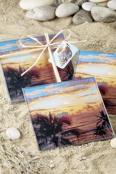 two cards with palm trees on them are tied to the sand and placed in front of some rocks