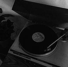 a record player sitting on top of a table next to a potted plant