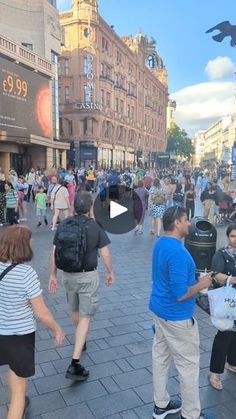 a crowd of people walking down a street next to tall buildings