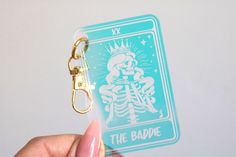 a hand holding a keychain with a skeleton on it