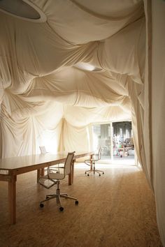 an office with white drapes covering the walls