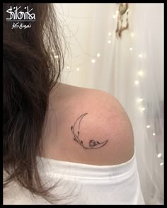 a woman's shoulder with a crescent tattoo on the left side of her neck