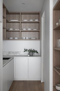 a kitchen with white cabinets and wooden shelves