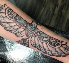 an owl tattoo on the arm is shown in black and grey colors with blue details