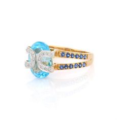 This is part of Chairish’s Fine Jewelry assortment.  Blue Topaz and Blue Sapphire Diamond ring in 18K Gold which perfectly goes with your personality and also helps you in learning and spiritual healing. This is a great bridesmaid, wedding or christmas gift for anyone on your list. Blue Topaz soothes, heals, stimulates, recharges, re-motivates your partner and aligns the meridians of the body – directing energy to where it is needed most.  Designed with Big Blue Topaz in center and halo of diamo Luxury Blue Birthstone Ring For Wedding, Blue Oval Birthstone Ring With Diamond Accents, Blue Diamond Ring With Gemstone Accents For Promise, Blue Diamond Ring With Gemstone Accents, Oval Shape, Blue Oval Diamond Ring With Gemstone Accents, Blue 14k Gold Hallmarked Birthstone Ring, Blue 14k Gold Birthstone Ring, Blue Topaz Wedding Ring With Gemstone Accents, Wedding Blue Topaz Ring With Gemstone Accents