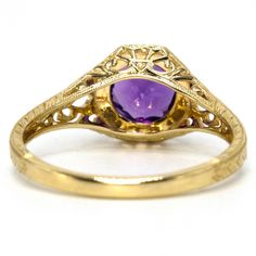 An approximate 0.93ct deep-purple amethyst is prong set in this lovely Edwardian style filigree mounting. The stone, nestled in an octagonal setting, is held in place with eight low profile prongs and surrounded by a circle of gold milgraining. The ring is beautifully filigreed and the band is embellished with a wheat style engraving. Added bonus: amethyst is the birthstone of February! Metal: 14K Yellow Gold Main Stone: 1 Round Cut Amethyst (approx. 0.93ct, 6.53 mm) Ring Size: 7.0 (can be sized