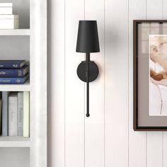 a black lamp is on the wall next to a bookshelf and bookcase