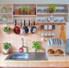 pots and pans are hanging on the wall above the sink in this small kitchen