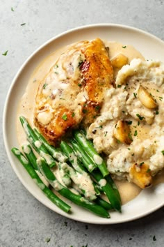 a white plate topped with chicken, mashed potatoes and green beans covered in gravy