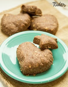 three heart shaped cookies on a blue plate next to some burlicks in the background