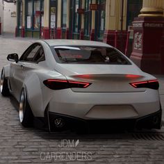 the rear end of a silver sports car on a cobblestone street