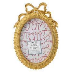 an ornate gold frame with pink ribbon on it