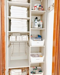 an organized pantry with white linens and other items in baskets on the bottom shelf