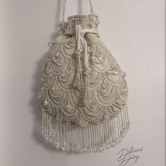 Step into a world of timeless elegance with our exquisite handmade ivory beaded bridal potli bag. Crafted with meticulous attention to detail, this enchanting accessory seamlessly blends tradition with modernity. Each delicate bead has been carefully chosen and skillfully hand-sewn. The potli bag's intricate beadwork showcases a stunning fusion of classic design and contemporary flair, making it a perfect match for brides seeking a touch of refined charm. The bag's compact size and comfortable h Elegant Cream Potli Bag With Handwork, Beige Bags With Pearl Embroidery For Reception, Elegant Beaded Shoulder Bag For Reception, Traditional Cream Bags For Reception, Elegant Embroidered Beige Potli Bag, Embroidered Cream Shoulder Bag For Wedding, Elegant Beige Embroidered Potli Bag, White Embroidered Potli Bag For Evening, Elegant Cream Potli Bag For Party