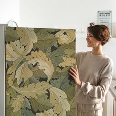 a woman standing in front of a painting holding it up to the camera with her hands