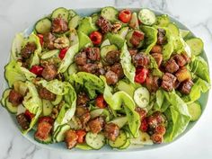 a white plate topped with lettuce, tomatoes and meatballs covered in sauce