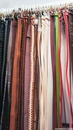 a bunch of different colored belts hanging on a wall