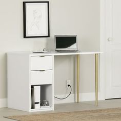 a laptop computer sitting on top of a desk next to a white cabinet with gold legs