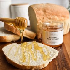 a wooden table topped with sliced bread and honey pouring from a jar onto the top