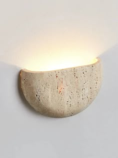 a light that is on the wall next to a white wall with a rock in it