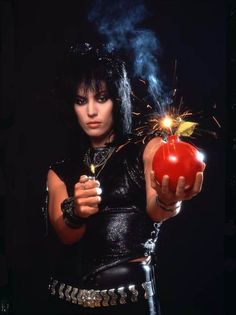 a woman holding an apple in her hand with a sparkler sticking out of it