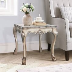 a table with a book, cup and vase on it in front of a chair