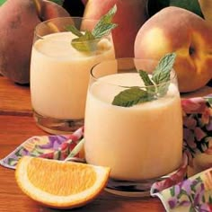 two glasses filled with orange juice and garnished with mint on a wooden table