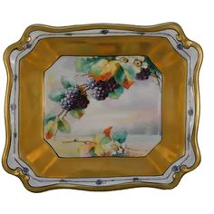 a gold and white plate with grapes on it