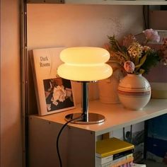 a lamp sitting on top of a table next to a vase with flowers in it