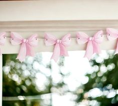 some pink bows are hanging from a window