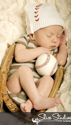 a baby laying in a baseball mitt holding a ball